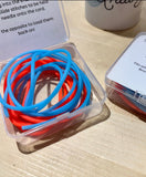 A set of hollow silicon stitch holder cords in red and blue, packaged in a clear plastic box with instructions.