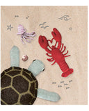 A printed catalog or booklet spread with a beige background, featuring a colorful beach-themed illustration on the left and a contents list on the right. The illustration shows a red lobster, a turtle, and a starfish on sand, while the right side lists chapter titles such as Crab, Lobster, Prawn, Sea Snail, and Techniques.