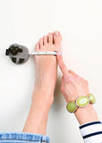 Book page with a hand wearing a green bracelet and a foot with a foot scrubber, text on the right side.