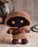 Crocheted Jawa amigurumi toy with text on a magazine page