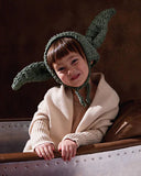 Child wearing a Grogu bonnet with a patterned background
