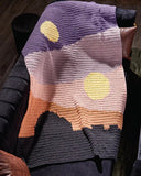 Crocheted blanket with a Tatooine landscape design on a couch.