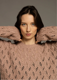 A person wearing a pink, lace-patterned crocheted sweater.