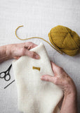 Darning project with yarn and needle, shown on a textured surface.