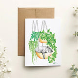 Greeting card with a cat and plants design on a light background with flowers.