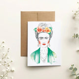 Frida Kahlo illustration on a card with a brown envelope and white flowers on a light background